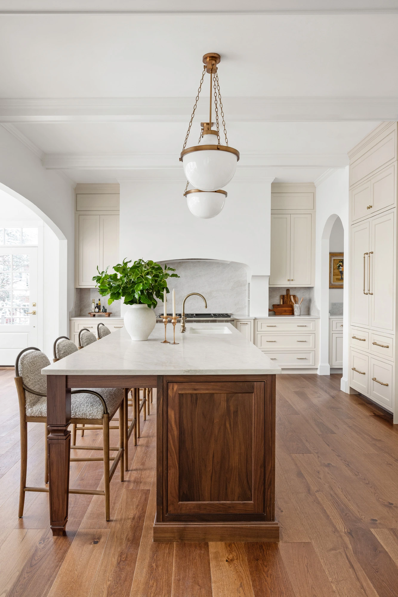 Kitchen island with marble countertop, brass globe chandelier and cream cabinetry at Project Three Ten on Blackstone Boulevard in Providence, Rhode Island